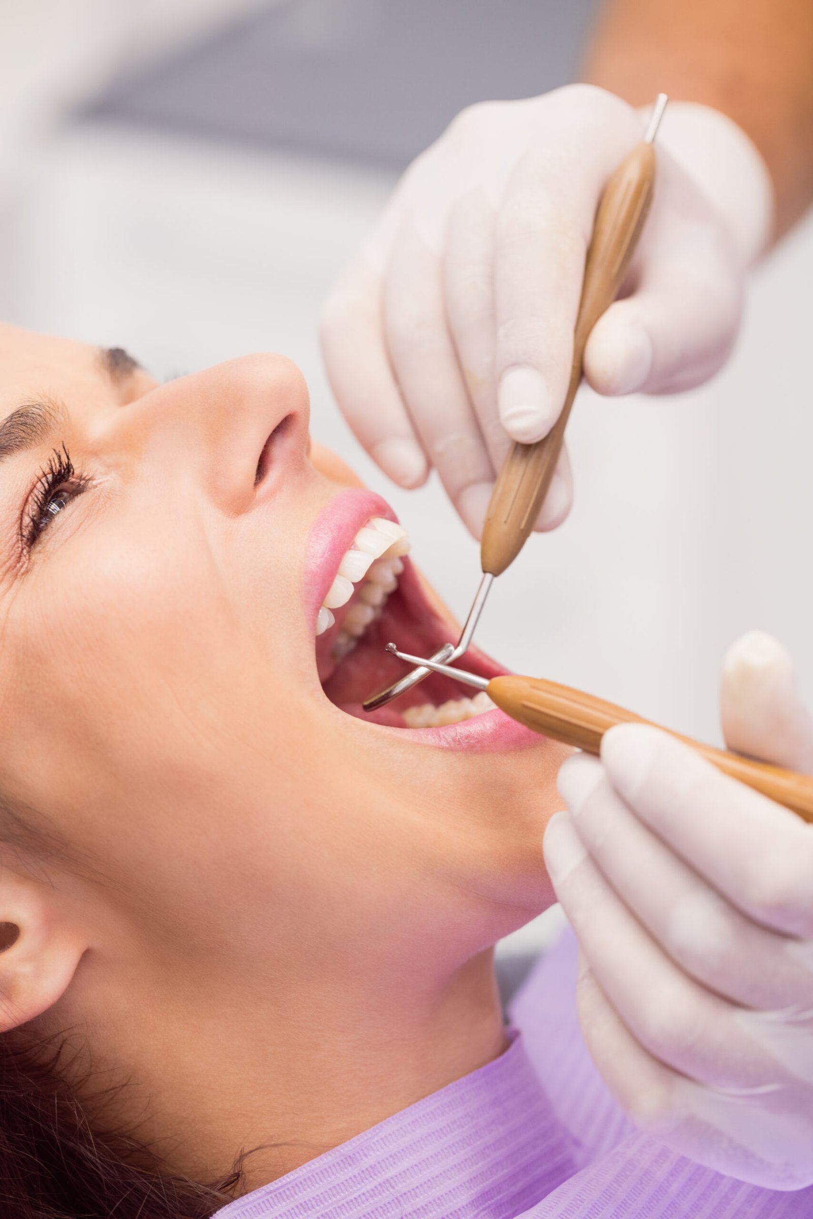 dentista-examinando-dientes-paciente-femenino-scaled.jpg