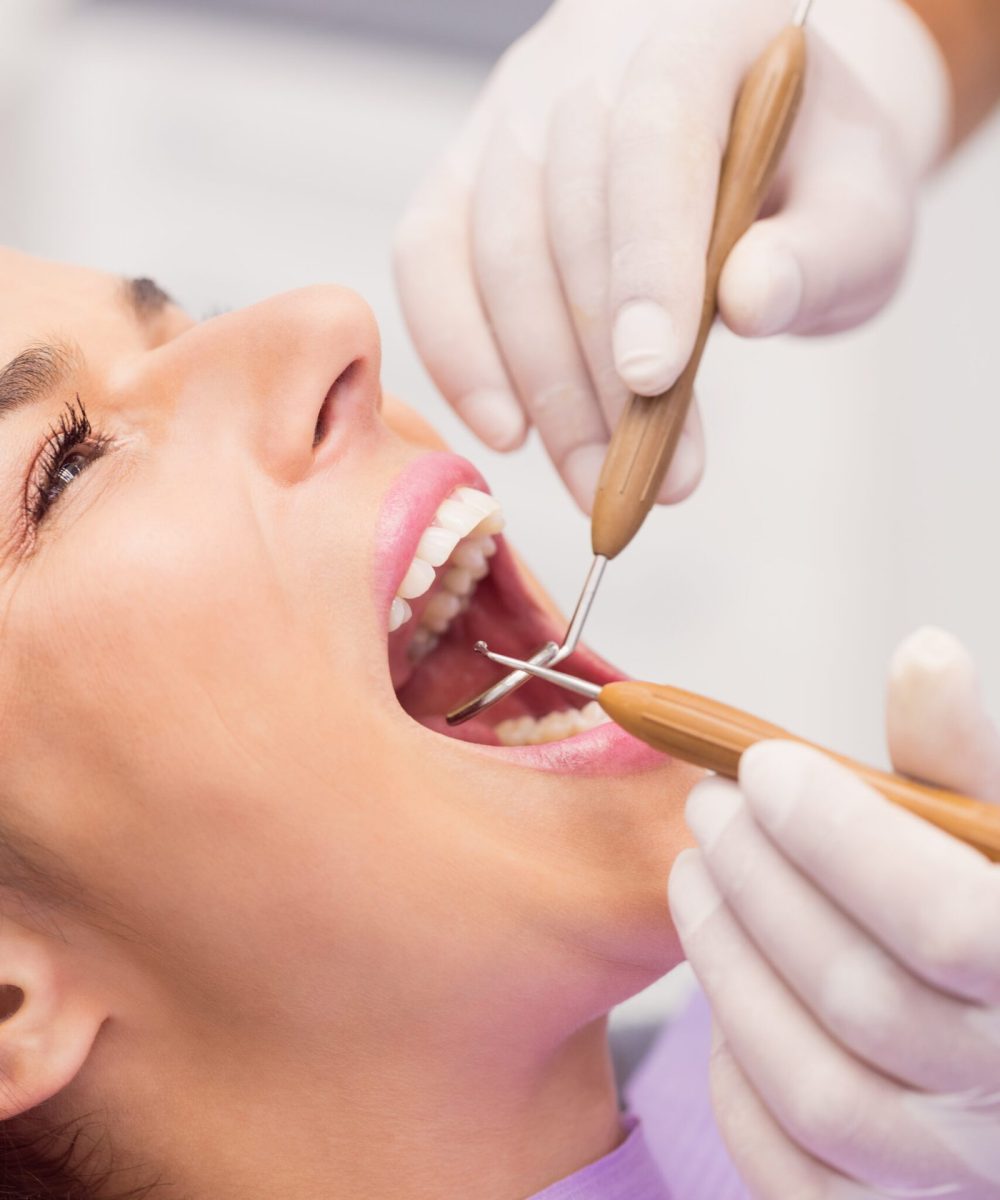 dentista-examinando-dientes-paciente-femenino-scaled-1.jpg